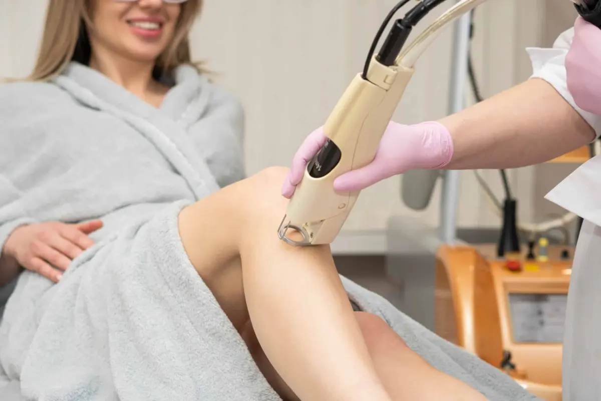 Bare HR Laser Hair Removal | Cosmetologist holds the maniple of the laser hair removal device along the slender beautiful legs of a woman, removing hair. laser hair and tattoo removal. laser rejuvenation | Sculpted Aesthetics in Columbia, SC
